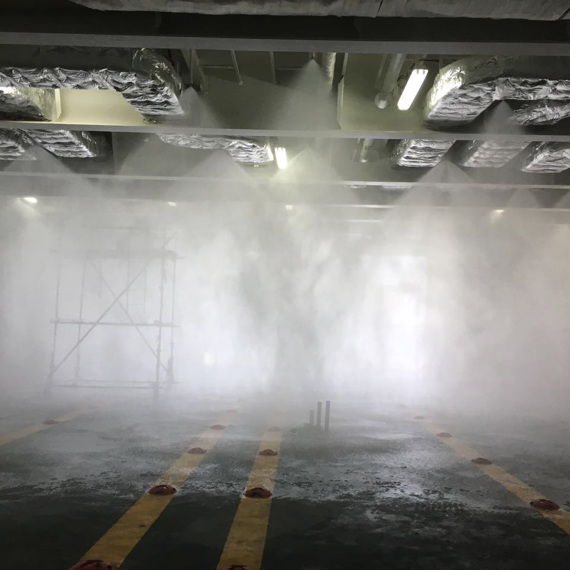 Test af sprinklersystem i et industrielt miljø med tåge og stillads.
