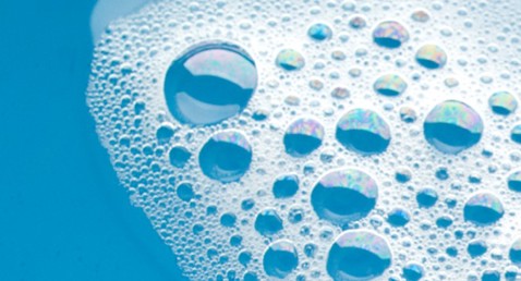 Sæbebobler flyder på blåt vand og viser iriserende farver.