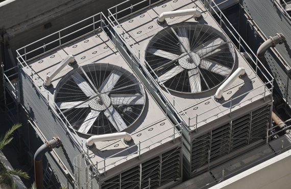 To store industrielle køleventilatorer på et tag, omgivet af sikkerhedsrækværk.