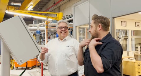 To mænd diskuterer i en industrifacilitet, den ene iført en DESMI-trøje.