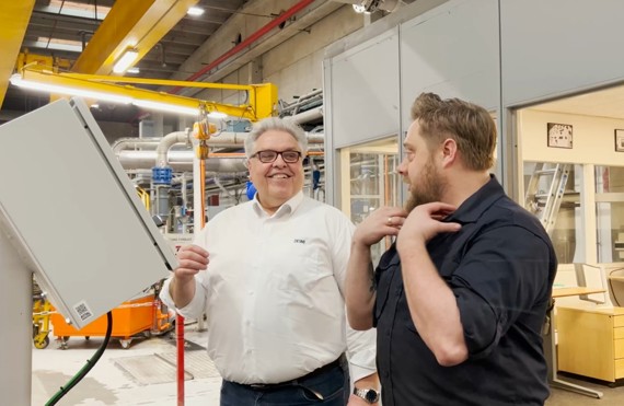 To mænd diskuterer i en industrifacilitet, den ene iført en DESMI-trøje.