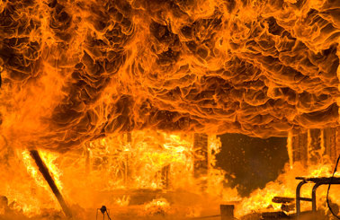 Intens ild opsluger en struktur med flammer og røg, der hvirvler dramatisk.