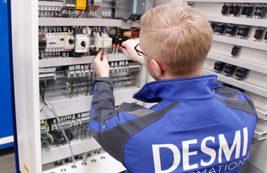 Tekniker i DESMI-uniform arbejder på ledningsføring i elektrisk kontrolpanel.