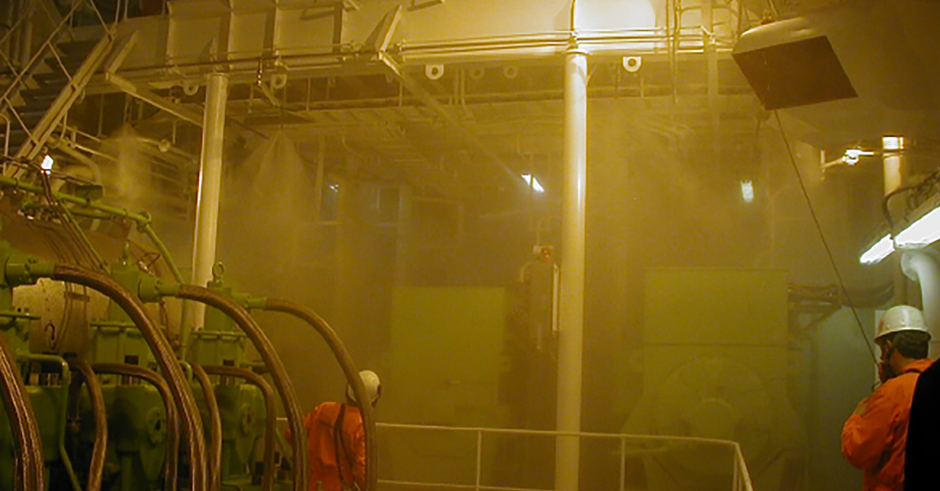 Industriområde med arbejdere i beskyttelsesudstyr midt i tung tåge og maskineri.