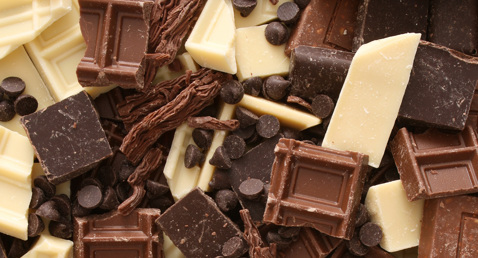 Blandede stykker af hvid, mælke- og mørk chokolade med chokoladestykker i en bunke.