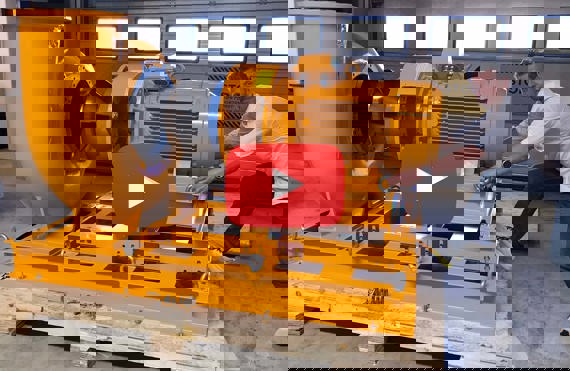 Mand justerer stor gul DESMI-pumpe i et industrielt miljø.