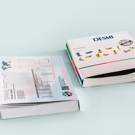 To DESMI reservedelskataloger på en lyseblå overflade.