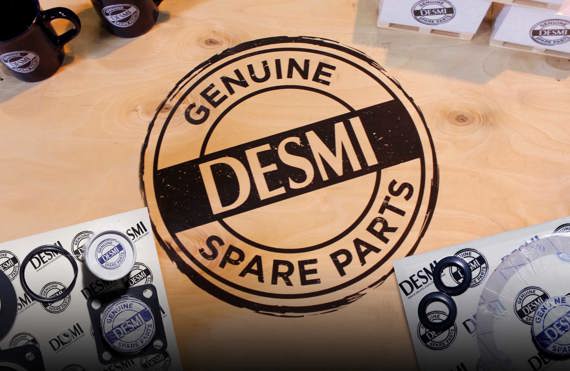 DESMI originale reservedele på en træoverflade med mærkekrus og emballage.