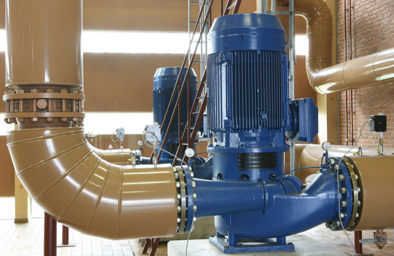 Industriel blå pumpe forbundet til store brune rør i en facilitet.