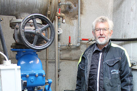 Mand står ved siden af en industriel ventil og rør i en mekanisk indstilling.