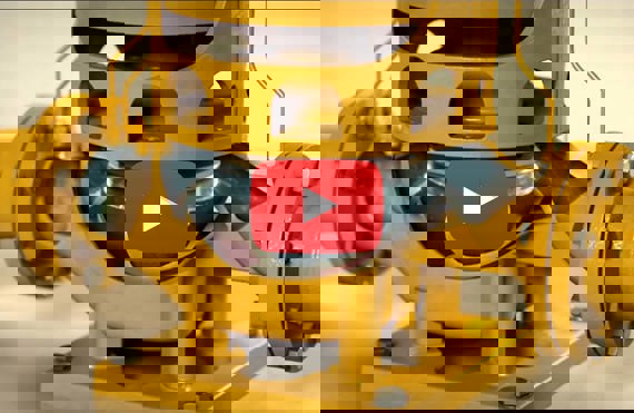 Gul industriel pumpe med synligt løbehjul, med et play-knap overlay.