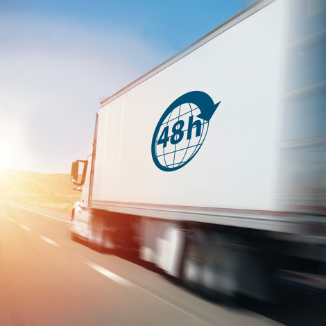 Lastbil med "48h" logo kører hurtigt ned ad motorvejen ved solopgang.