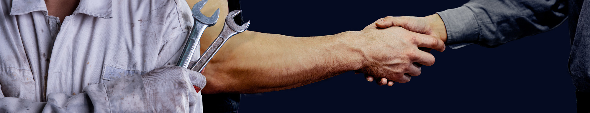 Mekaniker, der holder skruenøgler og giver hånd til en anden person i enighed.