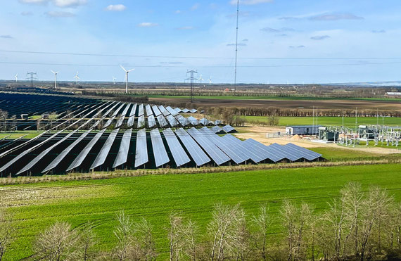 Solpaneler og vindmøller i et grønt landskab, European Energy-logo synligt.