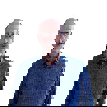 Smilende mand i en blå skjorte mod en ensfarvet hvid baggrund.