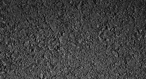 Nærbillede af ru sort asfalttekstur med synlige granulater og sten.