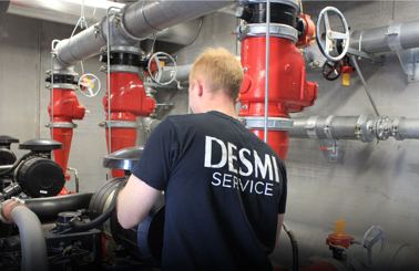 Tekniker i DESMI Service-skjorte arbejder med industrielt rørsystem.