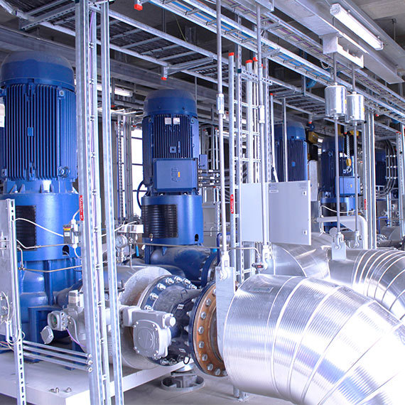 Industrielt rum med store blå DESMI-pumper og metalrør til håndtering af væsker.
