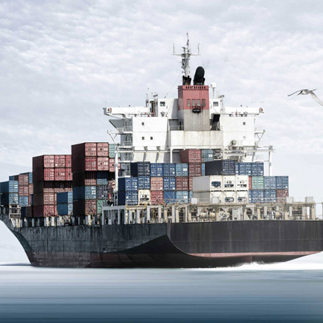 Stort fragtskib lastet med farverige containere sejler på et roligt hav.