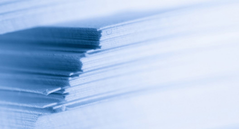 Nærbillede af stablede papirark med en blød blå nuance.