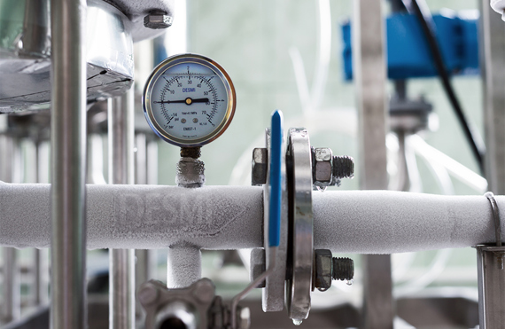 DESMI trykmåler på frostet industrirør til væskehåndtering.
