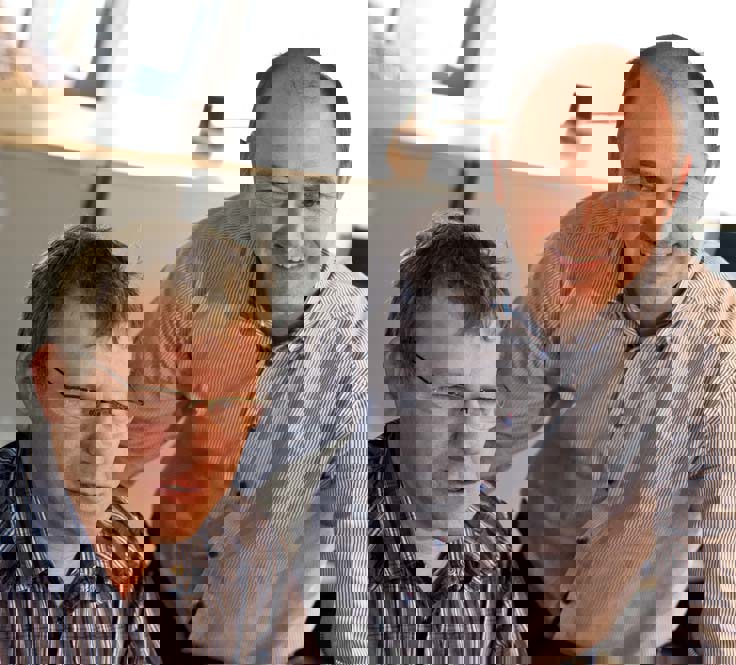 To mænd i stribede skjorter samarbejder i et kontormiljø.