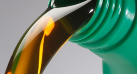 Gylden væske hældes fra en grøn plastikbeholder.