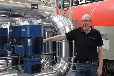 Mand står ved siden af industrielle pumper og rør i en mekanisk indstilling.